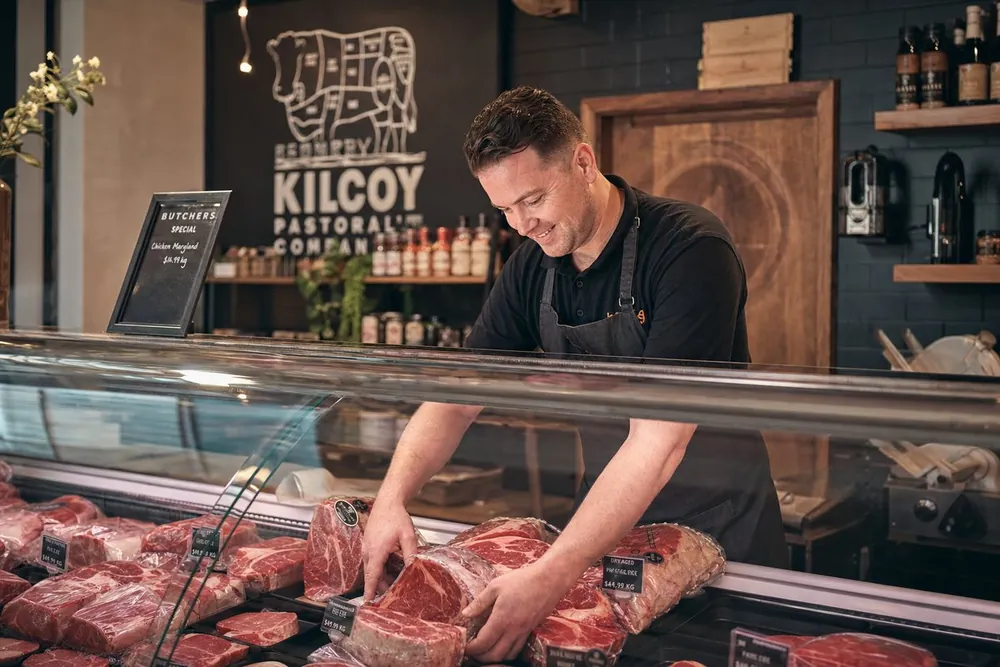 A butcher arranging premium cuts in a display case